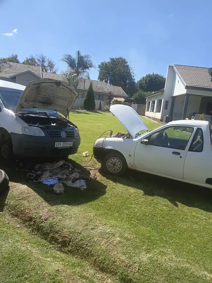 Two cars with open hoods parked on a residential lawn