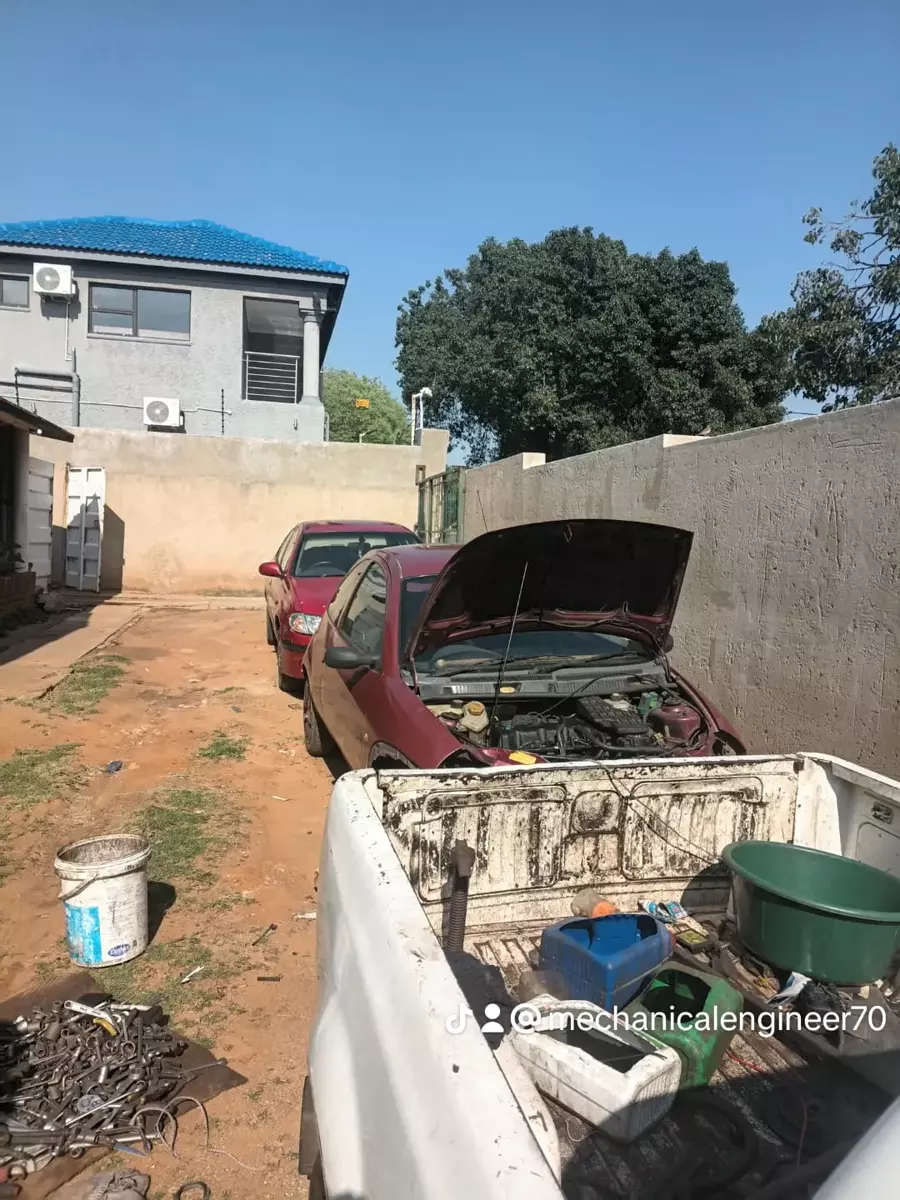 Cars being repaired in an outdoor yard with a pickup truck in the foreground